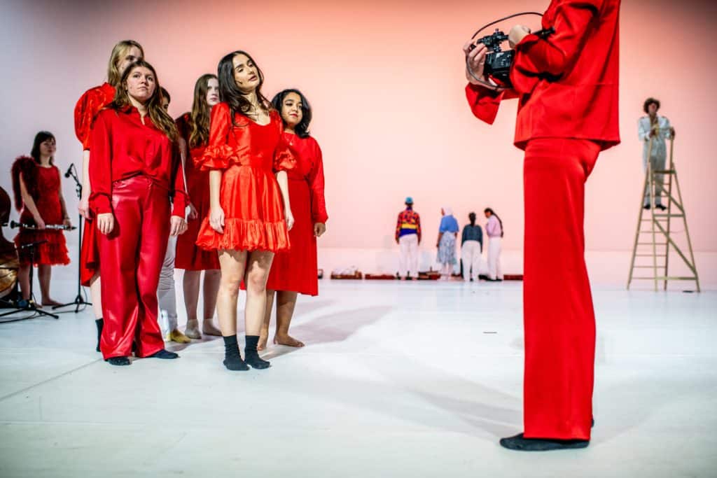 5 vrouwen in rode kleding op een podium
