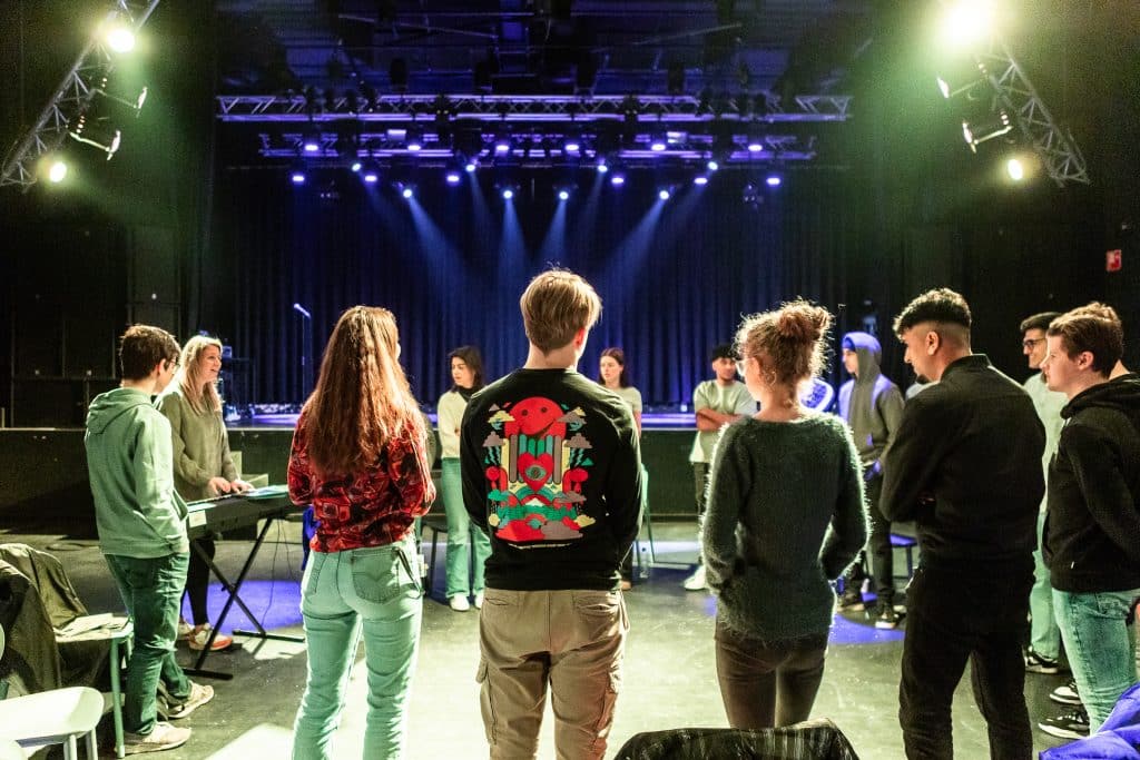 Meerdere mensen in een kring op het podium aan het repeteren