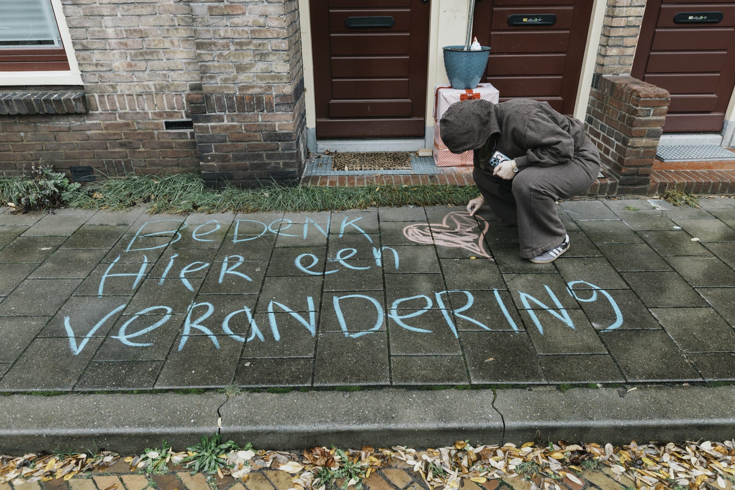 Iemand stoepkrijgt de boodschap 'Bedenk hier een verandering'