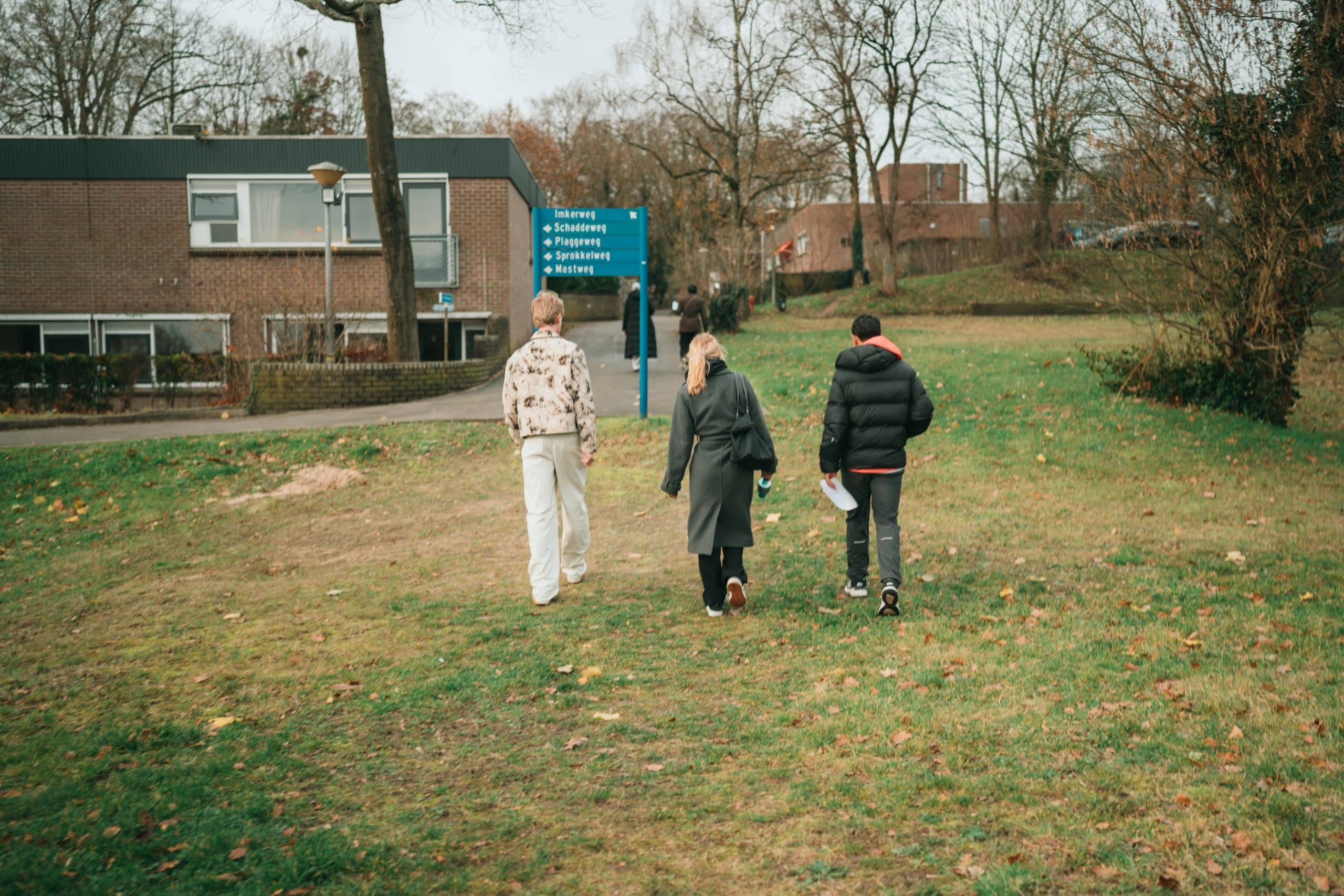 Drie mensen aan het wandelen op een grasveld
