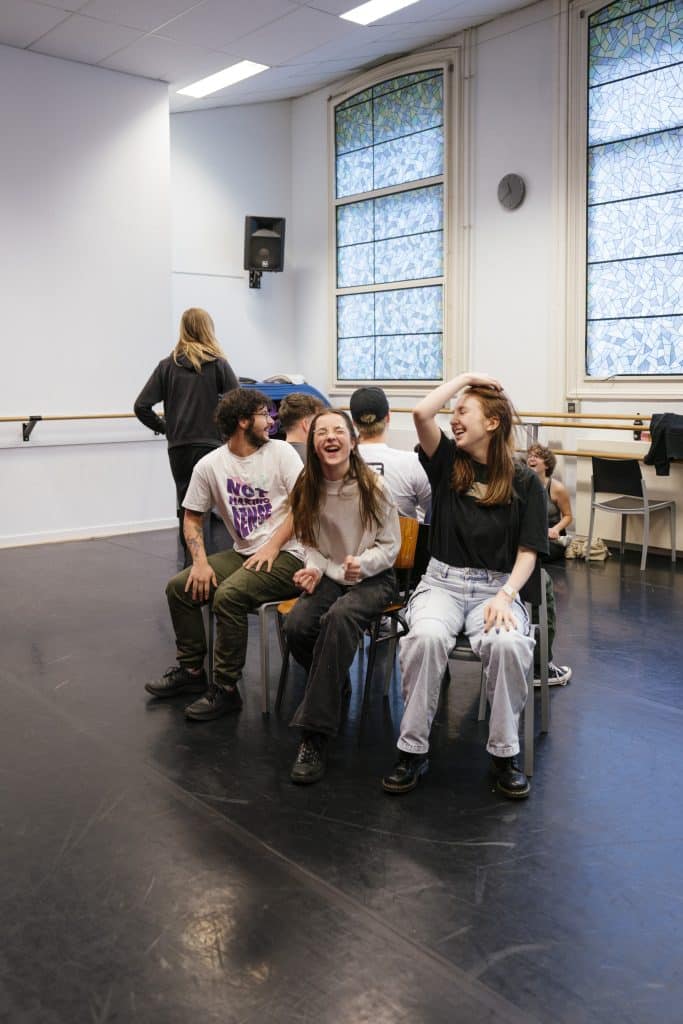 Lachende mensen op stoelen, tijdens een repetitie
