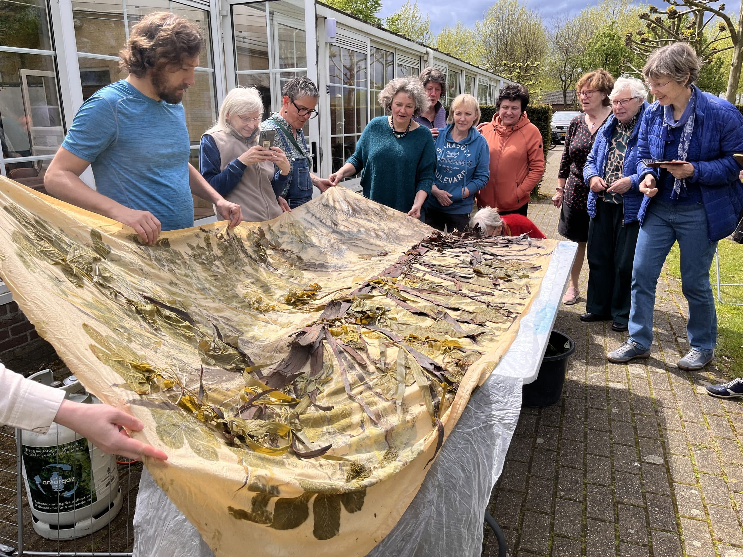 Groep mensen houdt een groot doek vast
