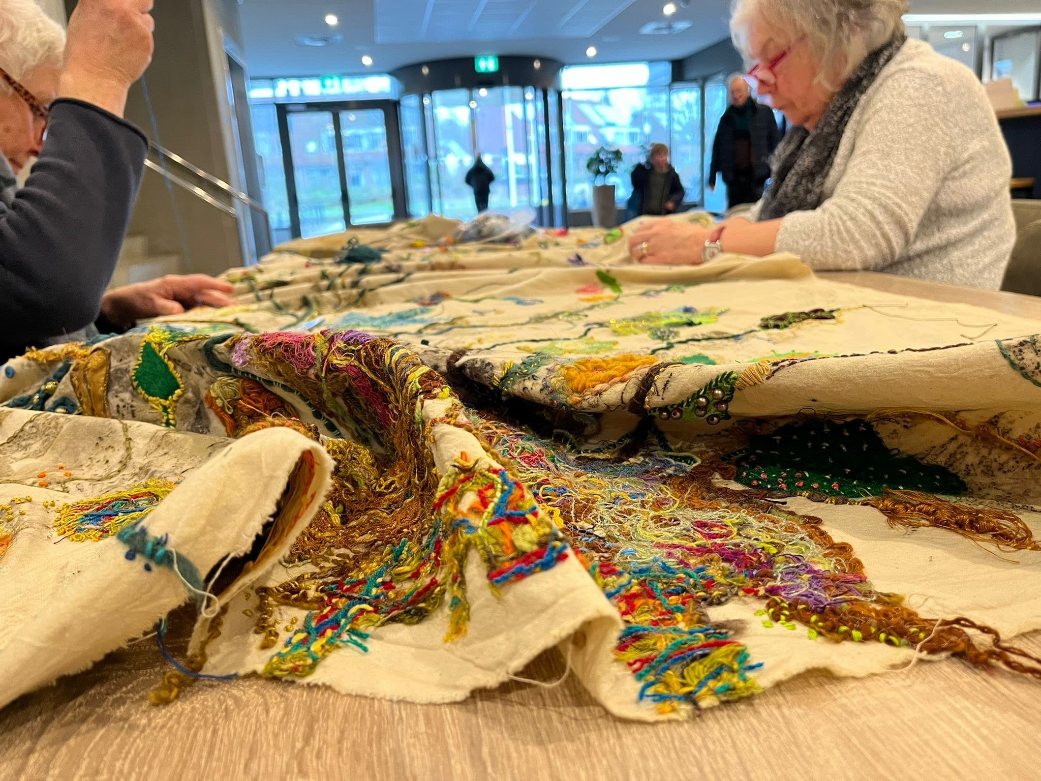 Mensen werken aan een geborduurd doek