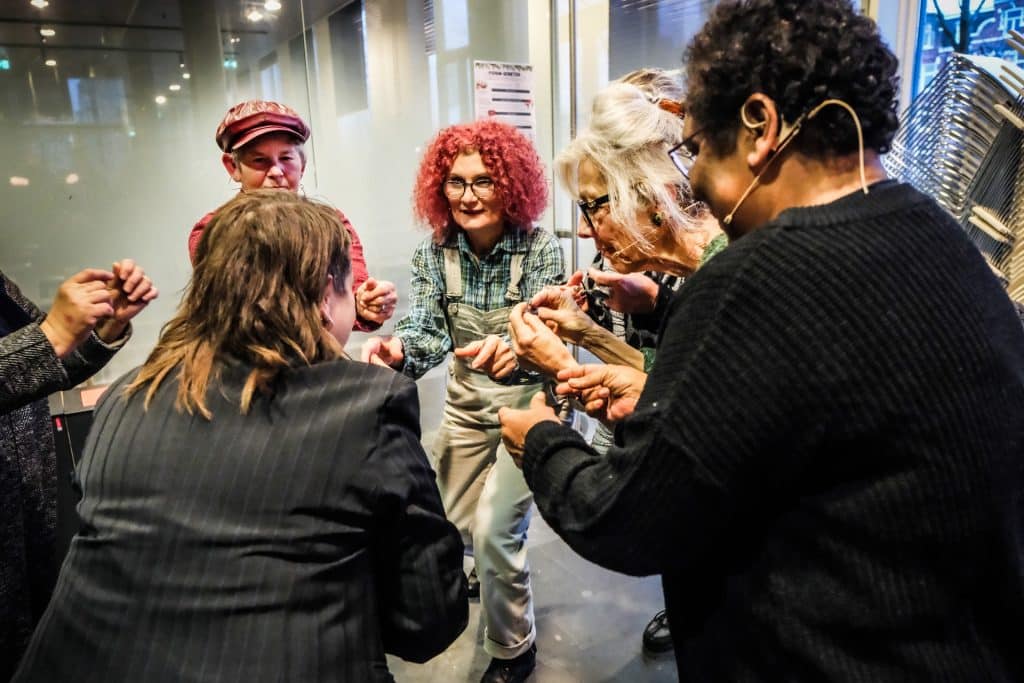 Meerdere lachende mensen met hun handen bij elkaar