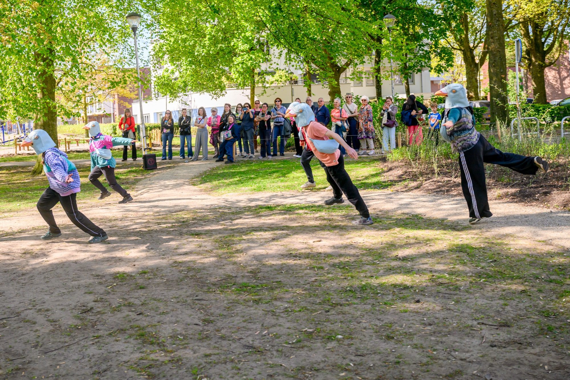 Acteurs met vogelmaskers in het bos voor een groep mensen