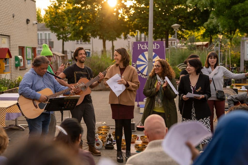 Een groep mensen maakt buiten muziek met twee gitaren