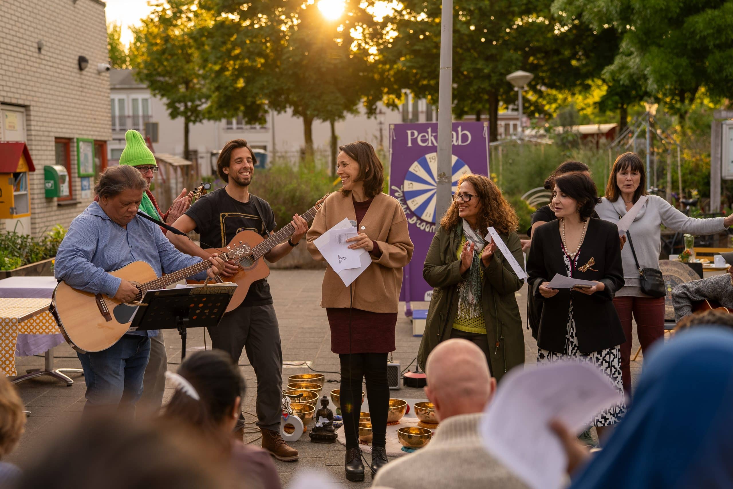 Een groep mensen maakt buiten muziek met twee gitaren