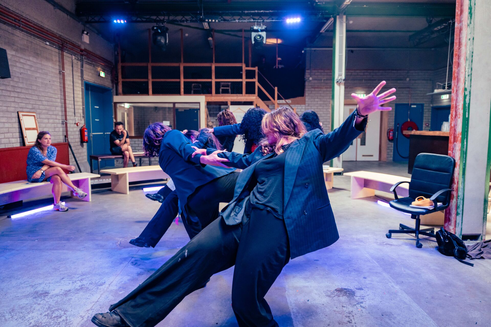 Jonge deelnemers voeren een expressieve bewegingsoefening uit in een theateromgeving.